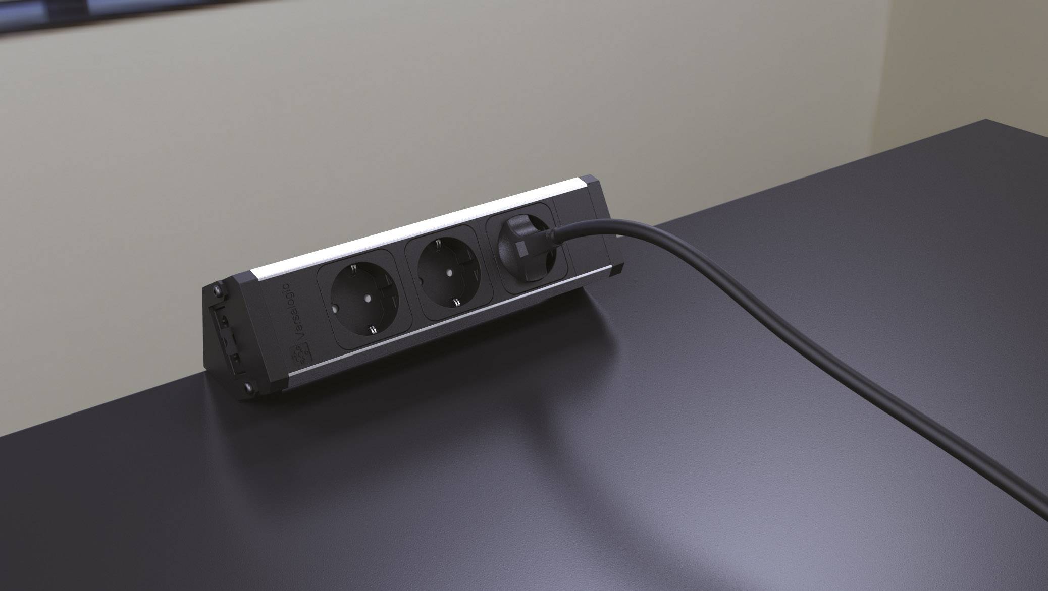 Power strip with two sockets sits on a black table, connected by a black cable.