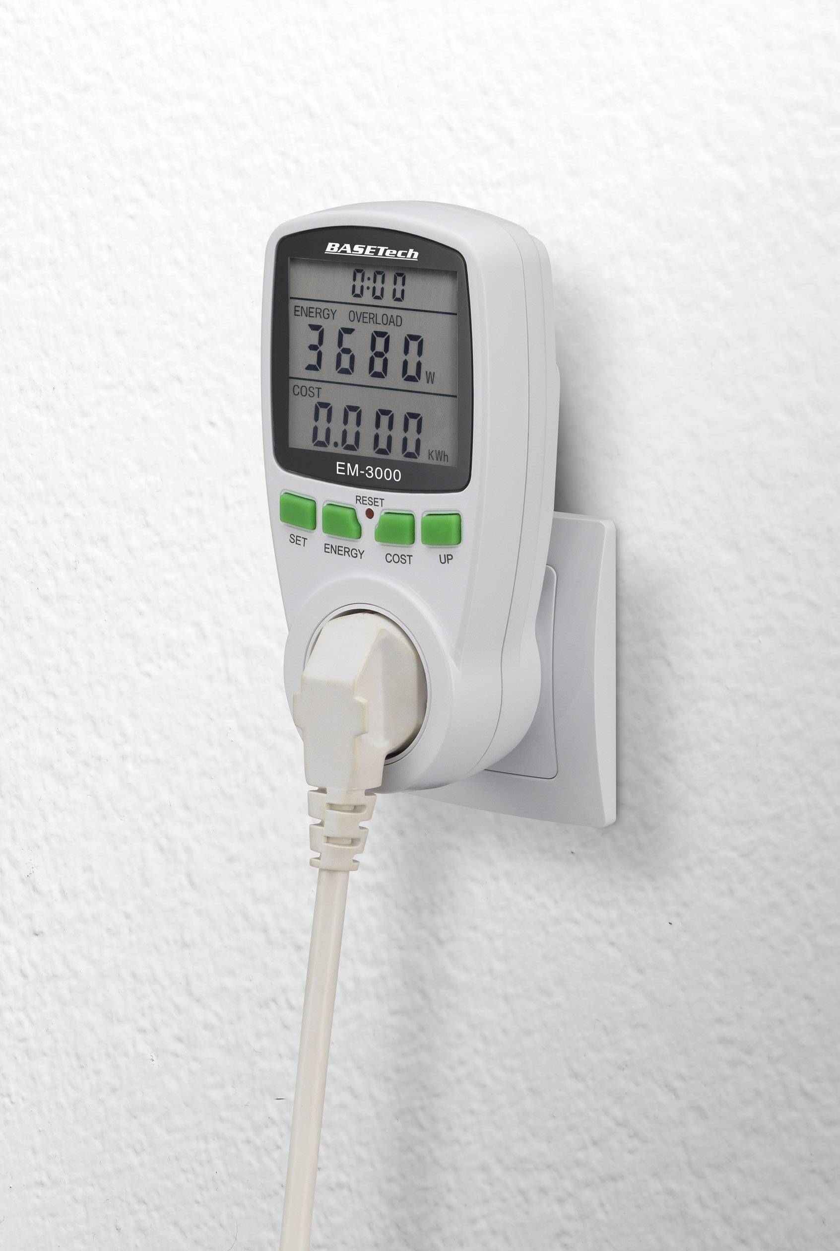 A power meter is plugged into a socket, displays consumption values on a digital display, and has a white border.