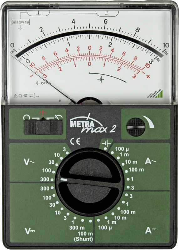 Analogue multimeter in a green casing, brand 'Metra max 2', displaying voltage and current on the scale. Rotary switch for function selection.