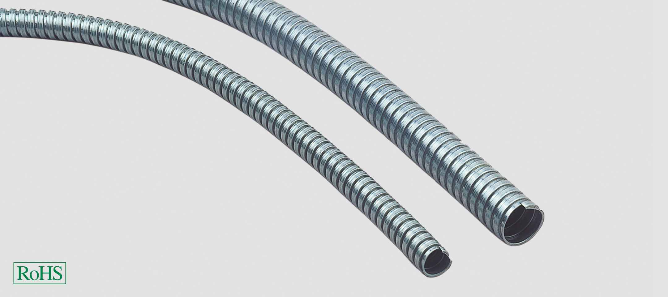 Two flexible metal pipes, one slightly thinner than the other, on a light background. A green 'RoHS' symbol is visible in the bottom left corner.