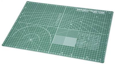 Green cutting mat with white measurement grid lines and angle diagrams, used for precise cutting and crafting.