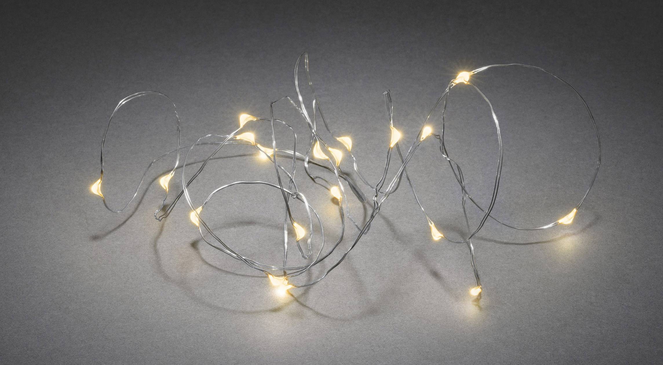 A loosely arranged string of lights with small warm white bulbs lies on a grey surface.