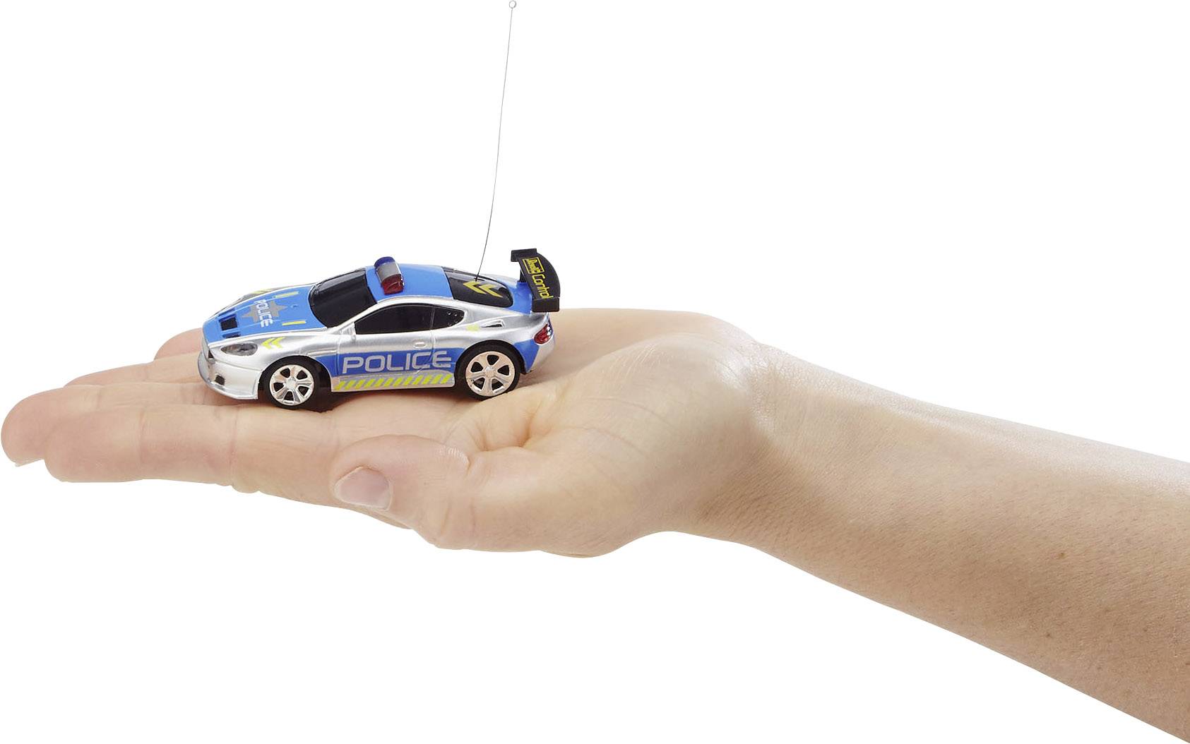 A hand is holding a small remote-controlled toy car in a police design with blue and white paintwork.