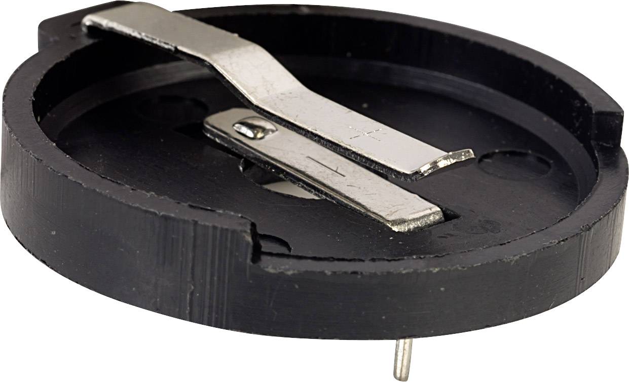 A round black cover with a metal clip stretched across its centre. It has small mounting pins on the underside.