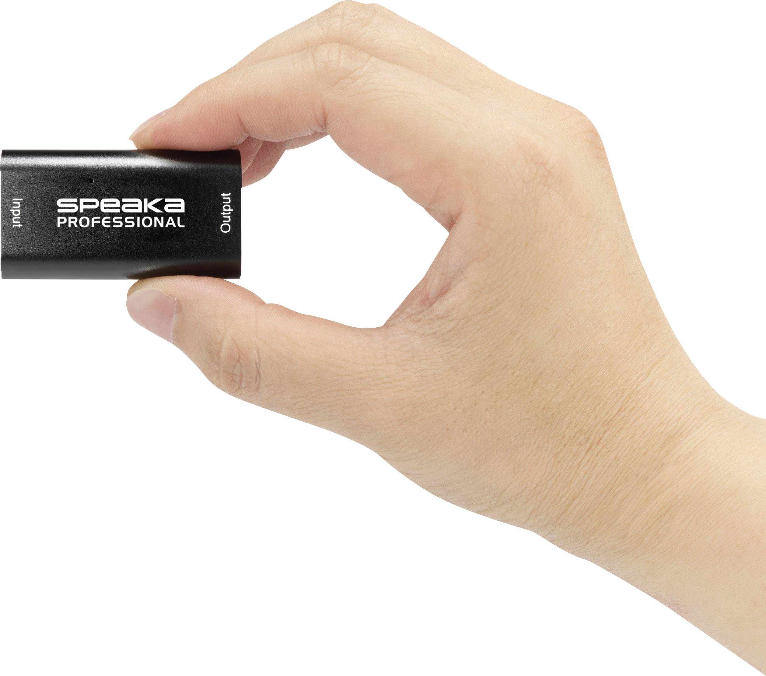 A hand is holding a small black adapter with the inscription 'Speaka Professional', with the ports 'Input' and 'Output' visible.