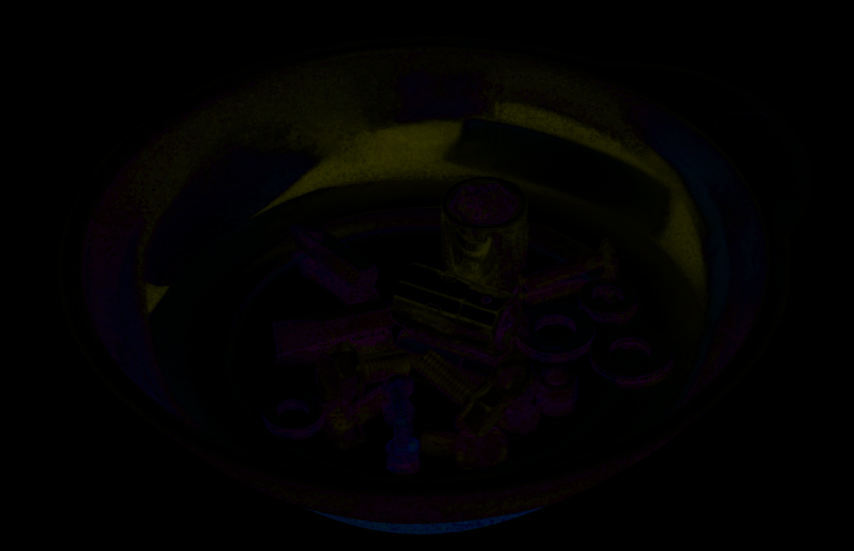 A metal bowl containing various screws, spanners, and nuts, used for tool storage.