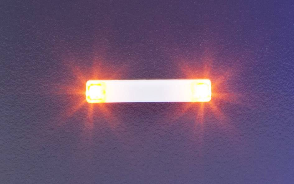 A slender, rectangular light bar with glowing orange light at both ends against a dark background.