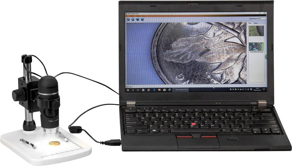 A laptop displays a close-up of a coin on the screen. A digital microscope is connected to the laptop and is examining the coin.