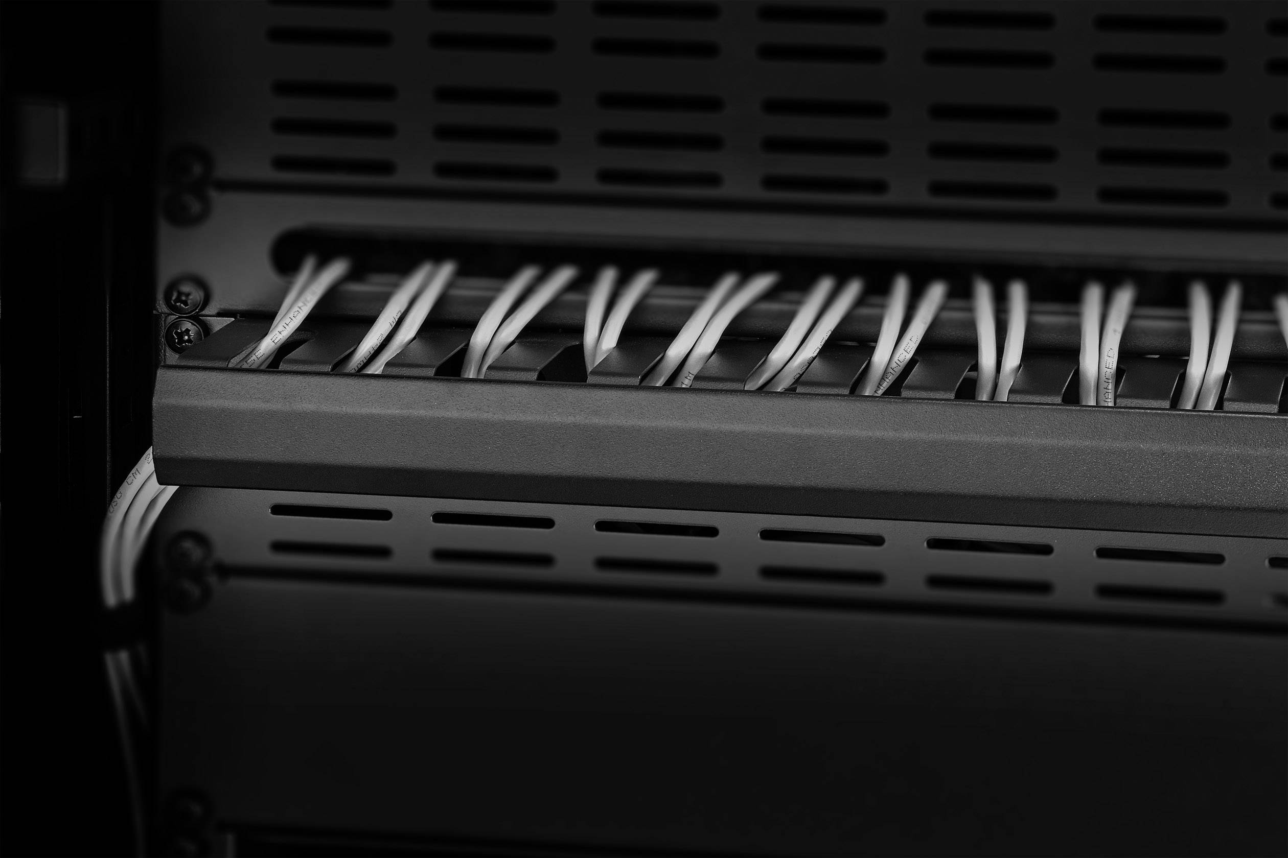 Black and white photograph of cables connected in a server rack. The cables run neatly through a cable management system.