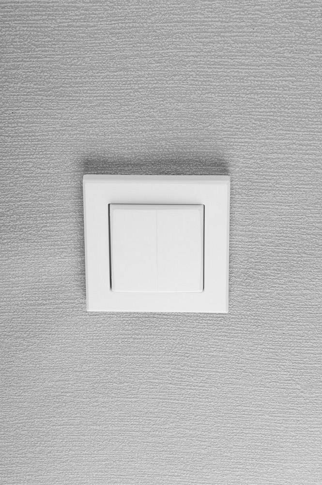 A white light switch on a grey wall.Note: In British English, I used the spelling 