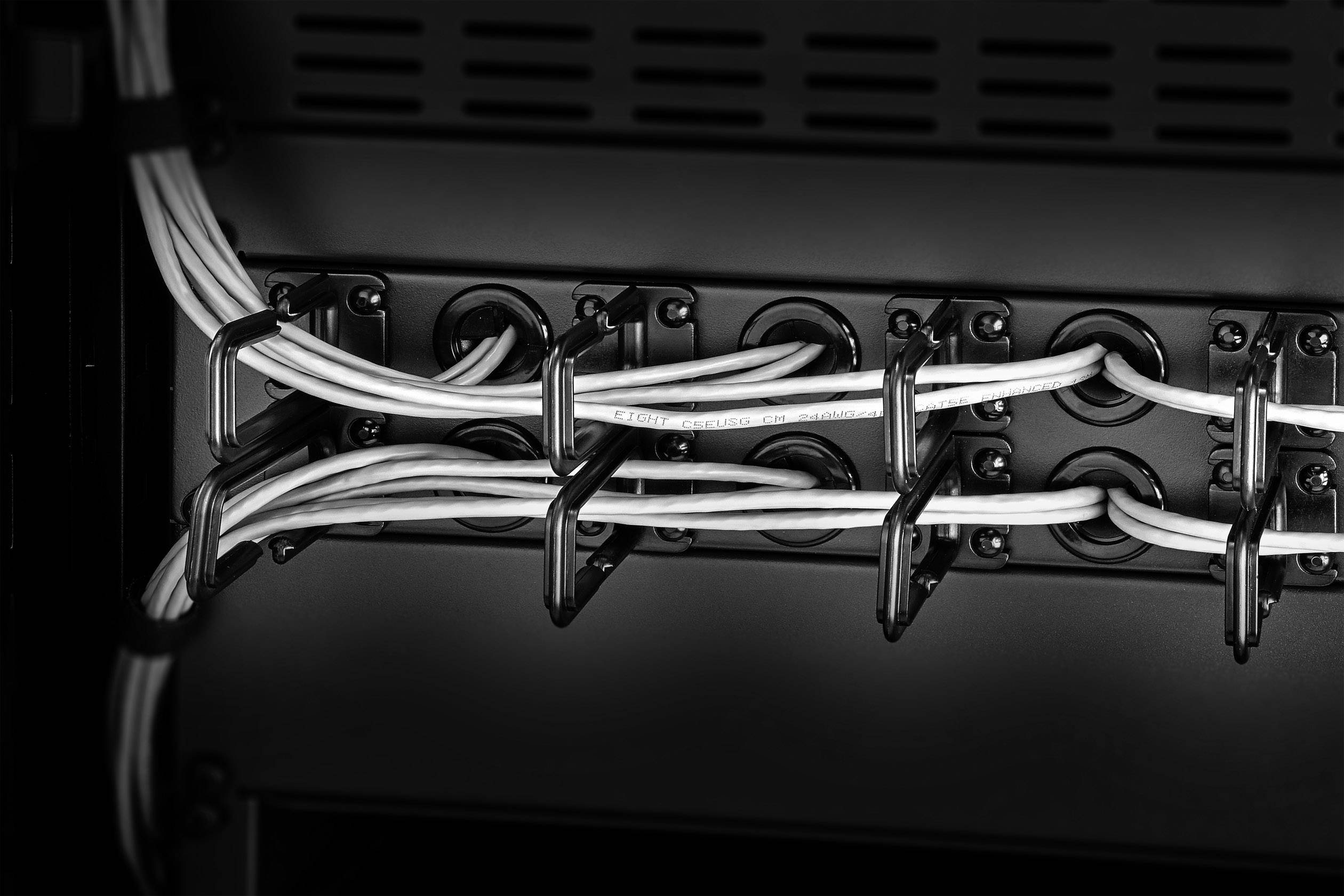 White cables are neatly secured in black cable clips on a back wall.