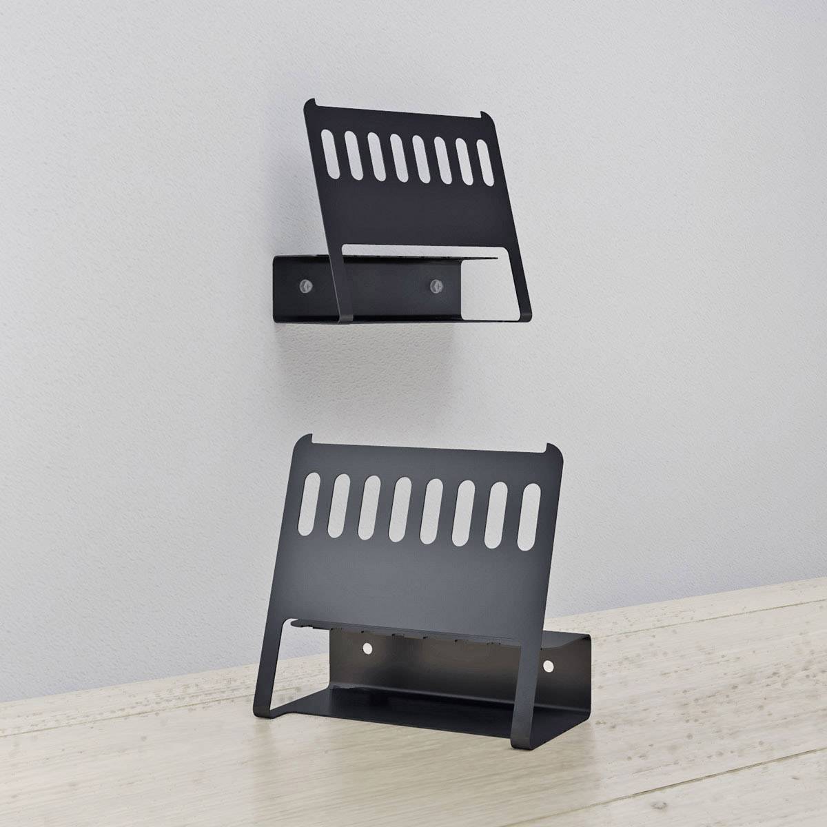 Two black, wall-mounted metal cable holders on a white wall and wooden table; keeping cables neatly in place.