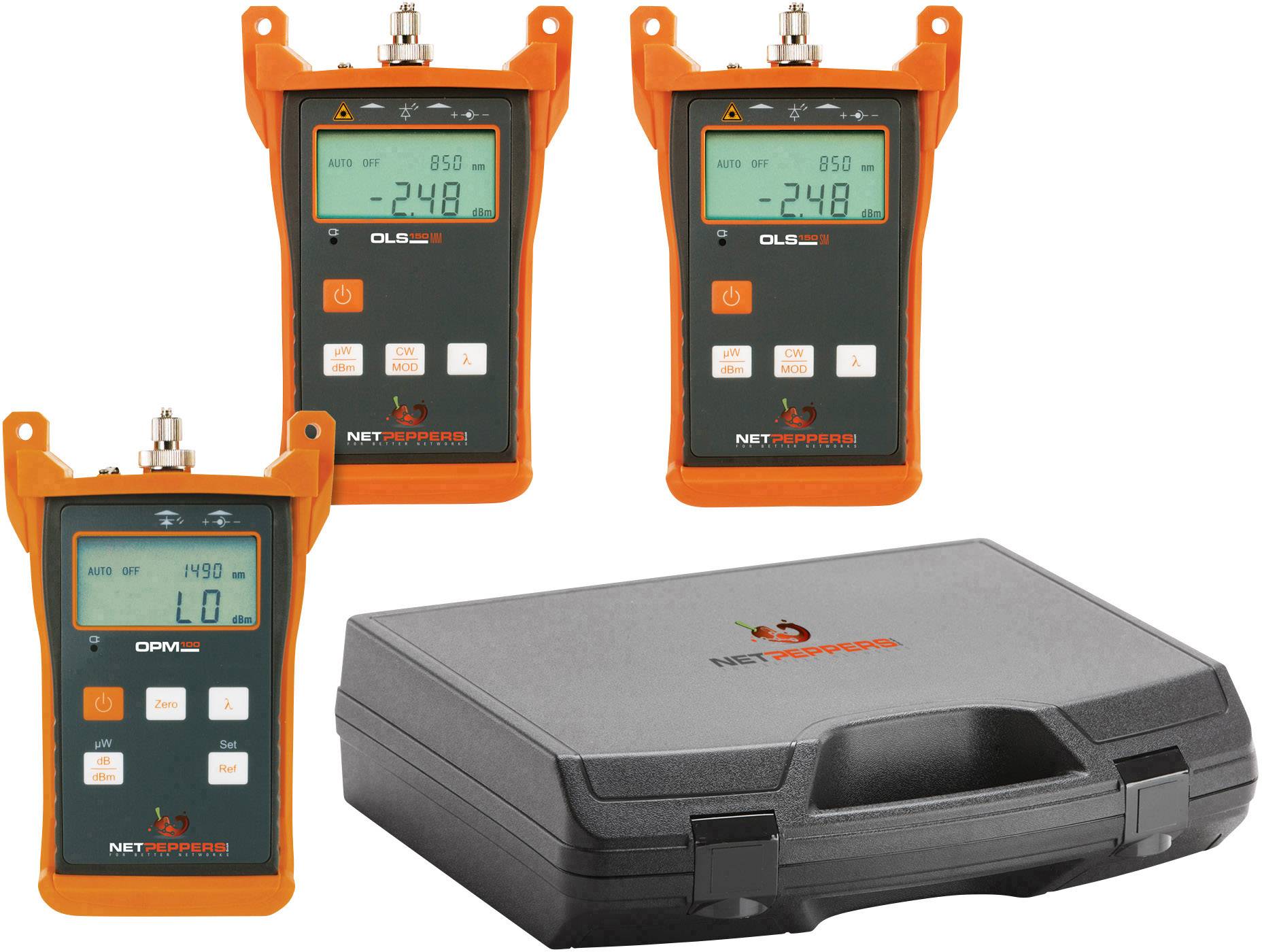 Three orange signal testers with digital displays on a table in front of a black hard-shell case.