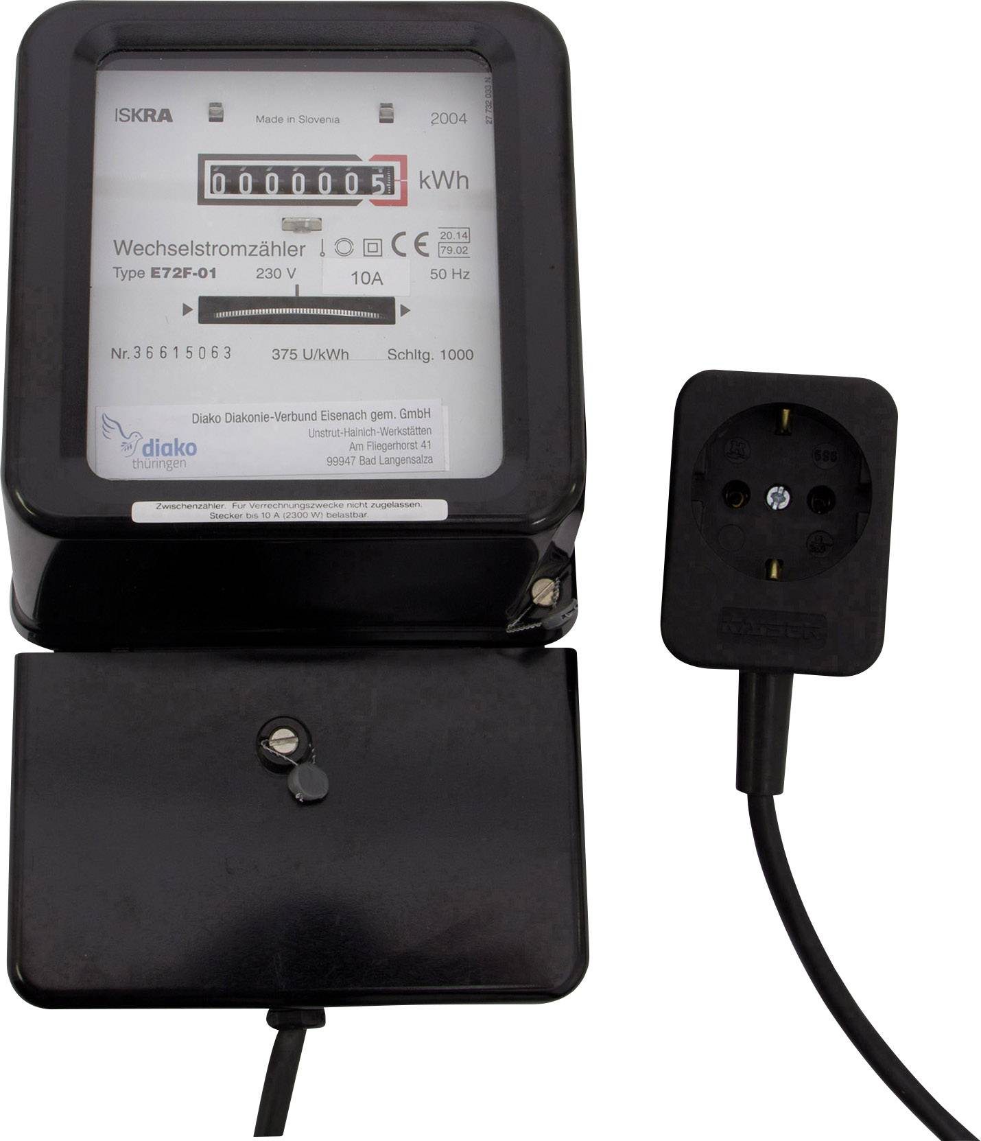 Electricity meter with an analogue display showing consumption in kWh. Beside it is a black plug with a cable.