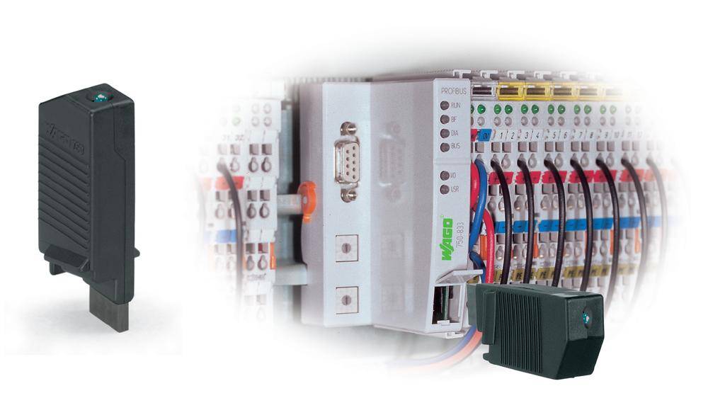 An electronic control unit with multiple ports is mounted in a control cabinet, surrounded by coloured cables.