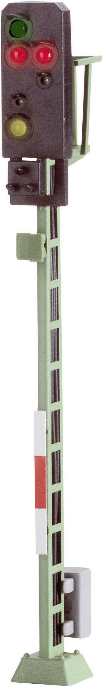 A railway signal displays green, red, and yellow lights. It stands on a green mast and regulates train traffic.