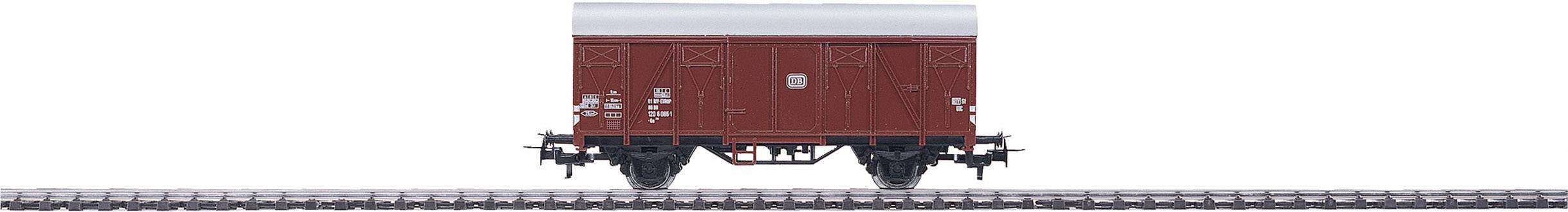A red goods wagon stands on a railway track. The wagon has a simple design and is free of any cargo.