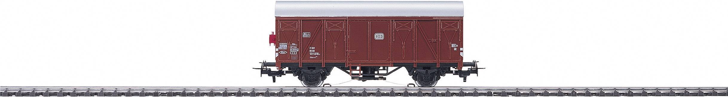 A red goods wagon is standing on a railway track. The wagon is viewed from the side, with its wheels and axles visible.