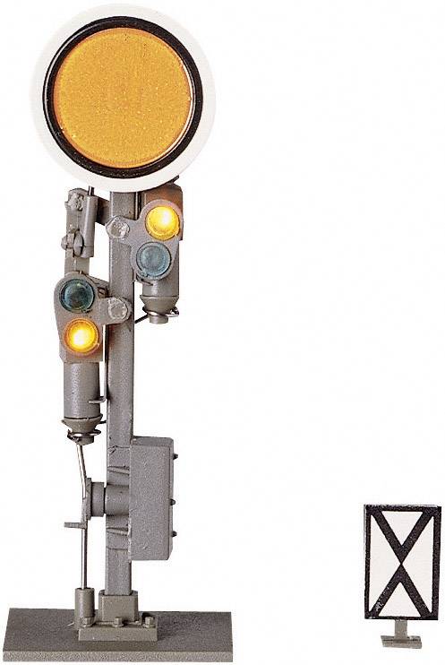 Model of a railway signal with an illuminated yellow main signal and two small light signals. Signal board with a cross underneath.