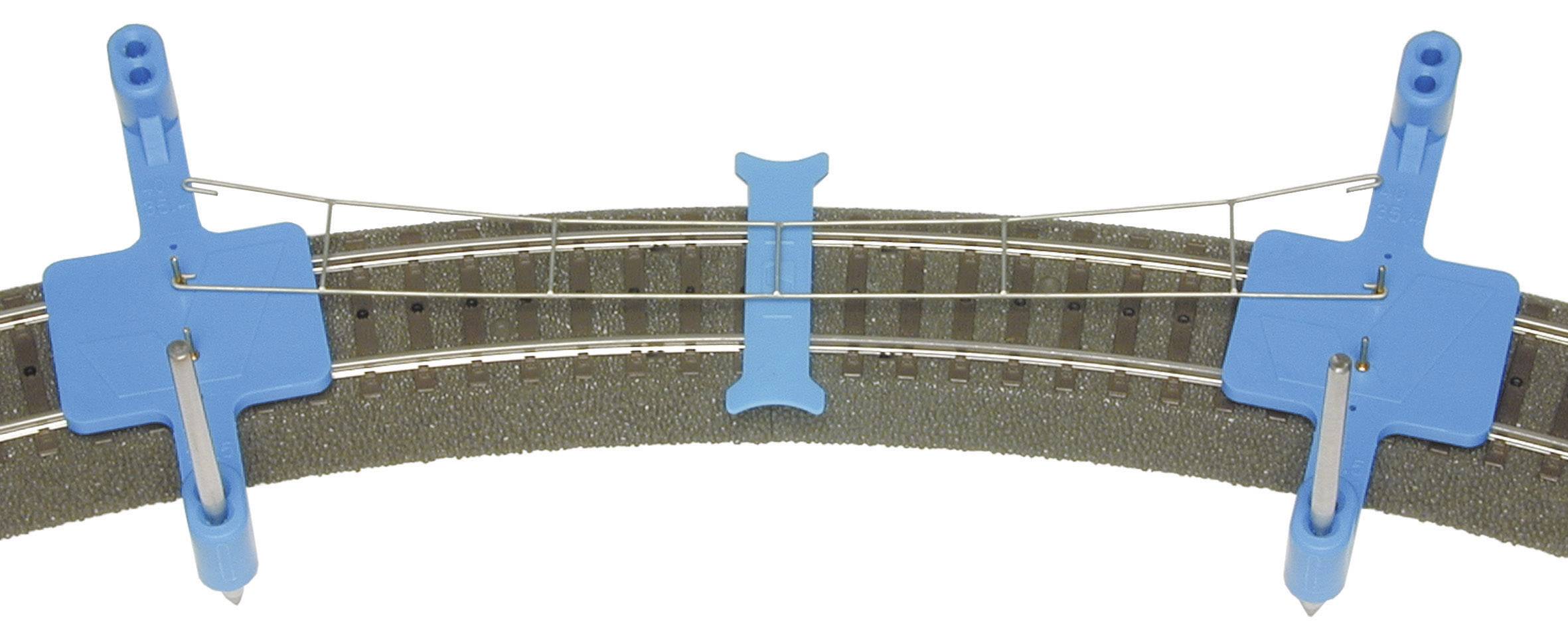 Two blue, hooked clamps on a rail section, connected by wire. For securing tracks in model railway construction.