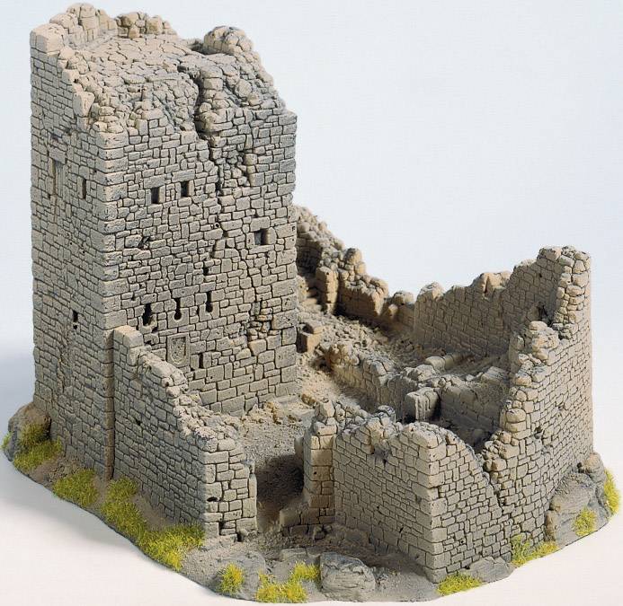A miniature model of an old castle ruin with textured stone walls and partially collapsed walls on a grassy base.