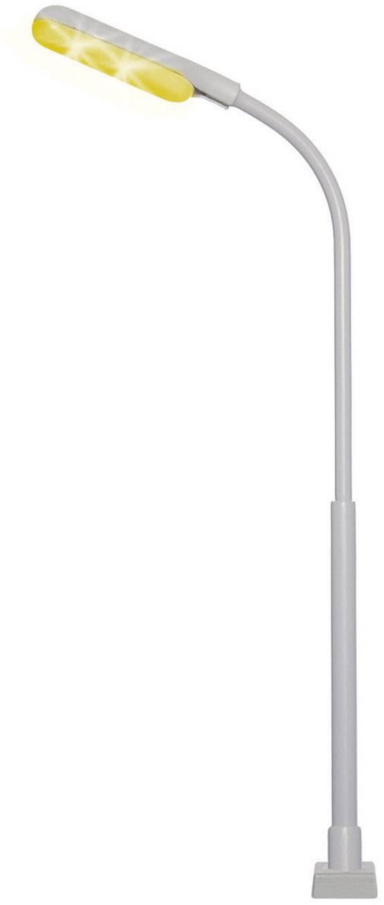 A modern, curved street lamp with yellow light against a grey background.