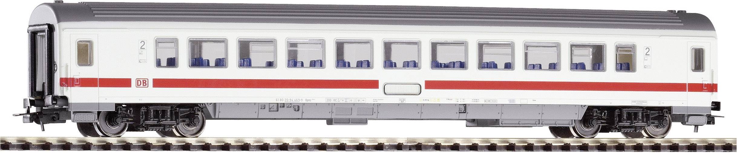 A white passenger carriage with a red stripe from Deutsche Bahn is standing on railway tracks. Several windows with blue seats are visible.