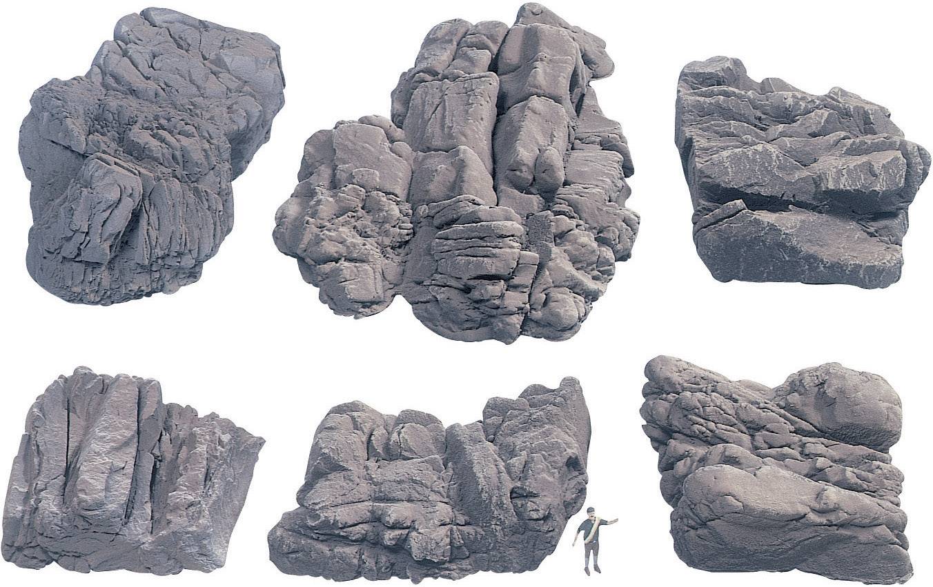 Six large rocks arranged in various shapes and textures on a light background. A small human figure beside them indicates the scale.
