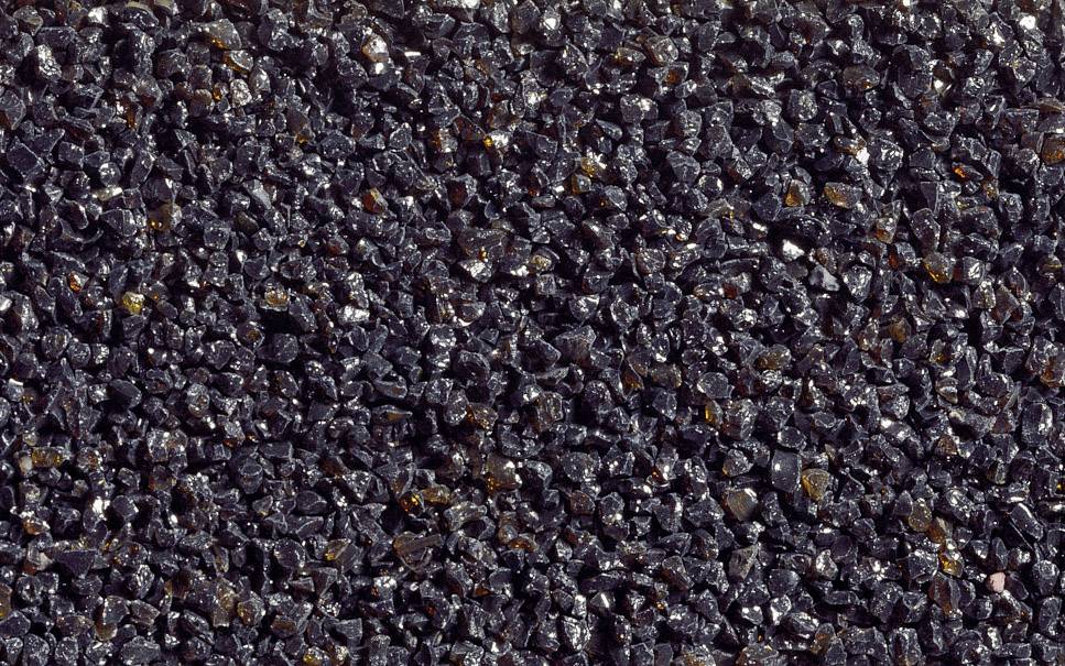 Close-up of a texture composed of numerous small, dark stones or grains tightly packed together, forming an uneven surface.