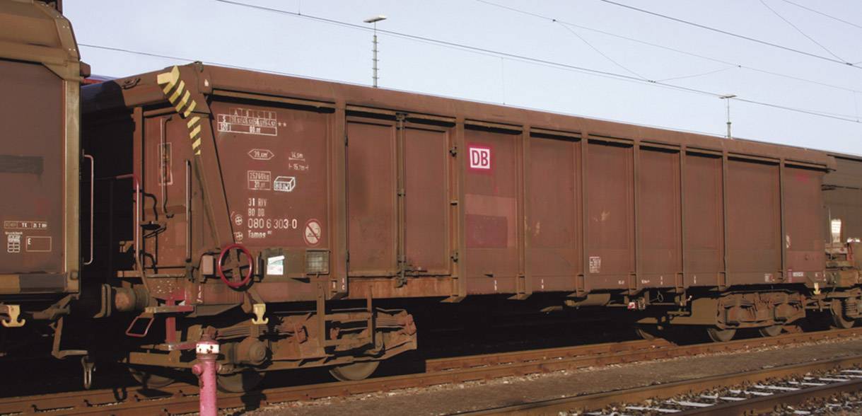 Freight wagon of Deutsche Bahn on a railway track. Dark red wagon colour with multiple freight stickers and DB logo visible.