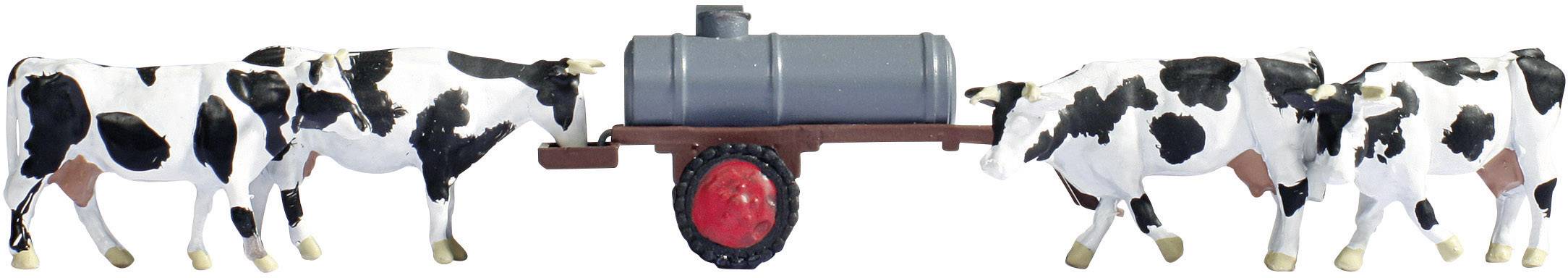 Four black and white cows are pulling a grey milk tanker trailer. The trailer has a red wheel.