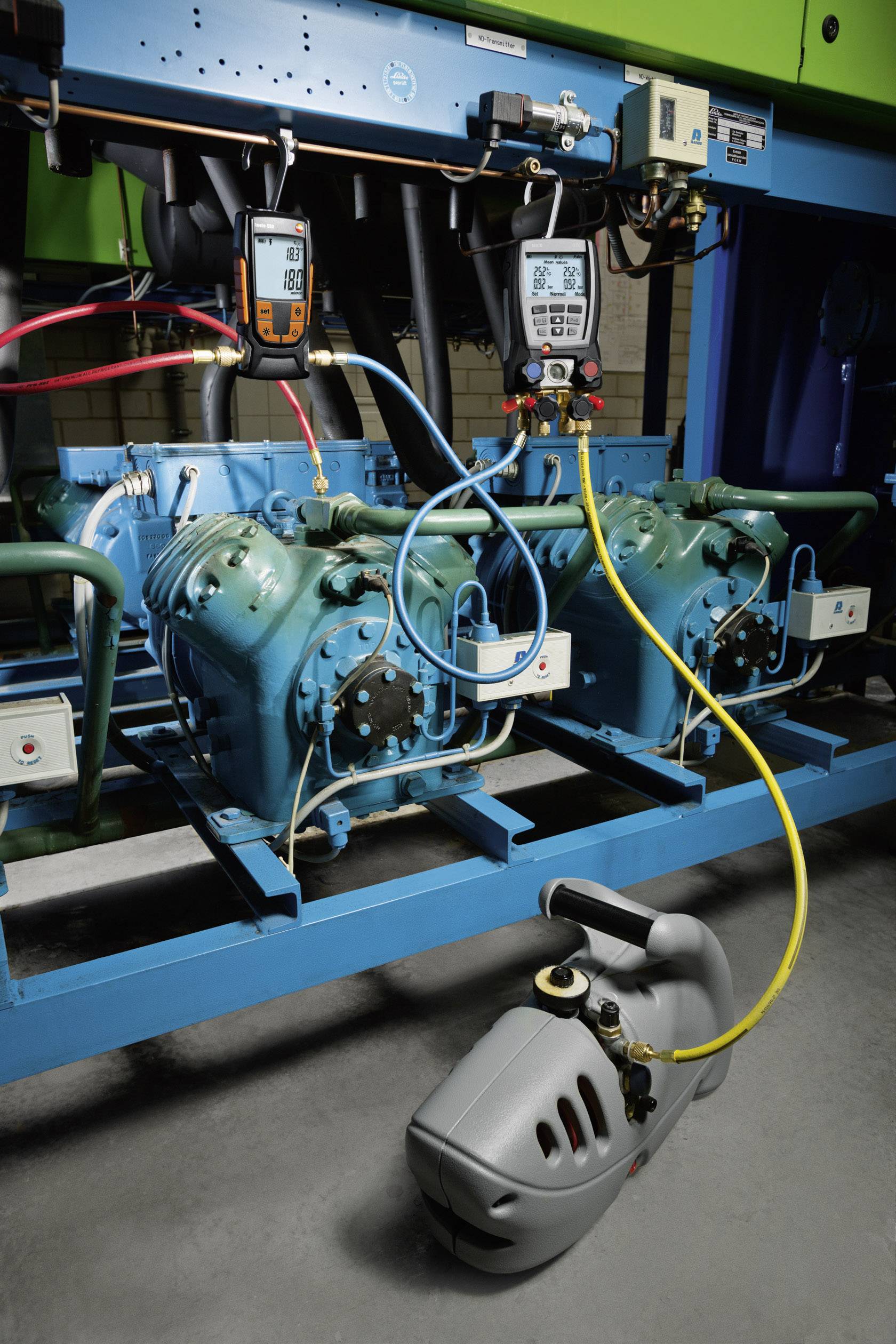 Industrial cooling system with two compressors. Diagnostic tools measure operational values. Environment appears technical and functional.