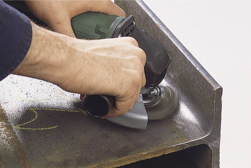 A person is grinding a metal surface with an angle grinder to smooth or process it.