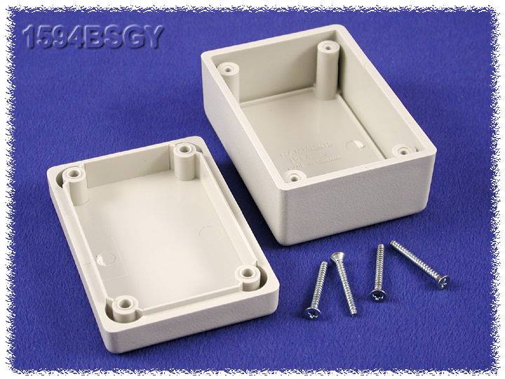 Grey, rectangular plastic enclosure in two parts with four screws on a blue background.