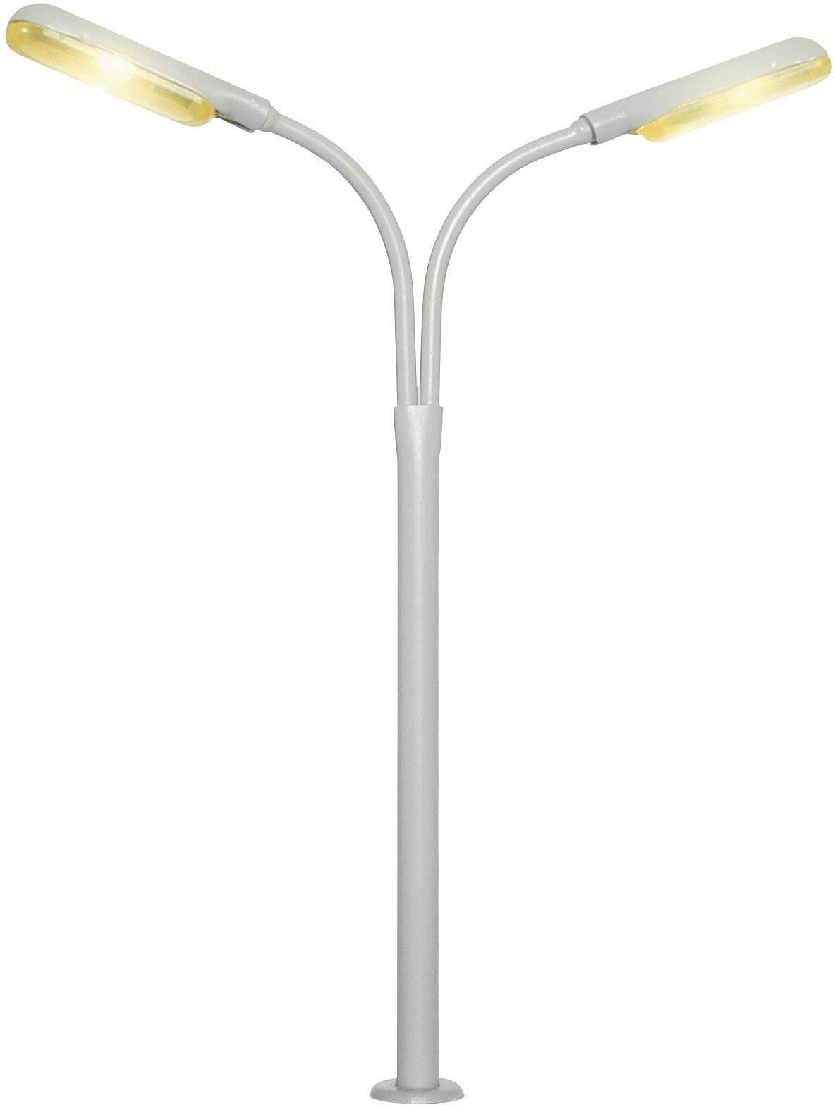 A silver-coloured modern street lamp with two outward-curving arms and illuminating LED lights emitting warm light.