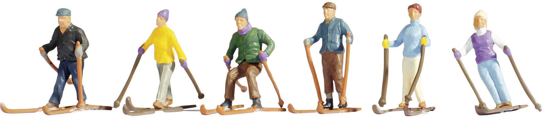 Six miniature figures of skiers in colourful clothing, each with skis and ski poles, on a white background.