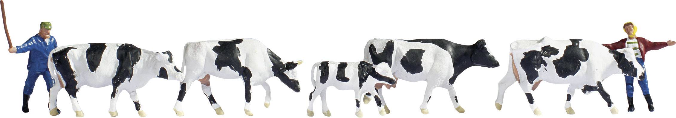 Two figures in workwear are leading a line of black and white cows.