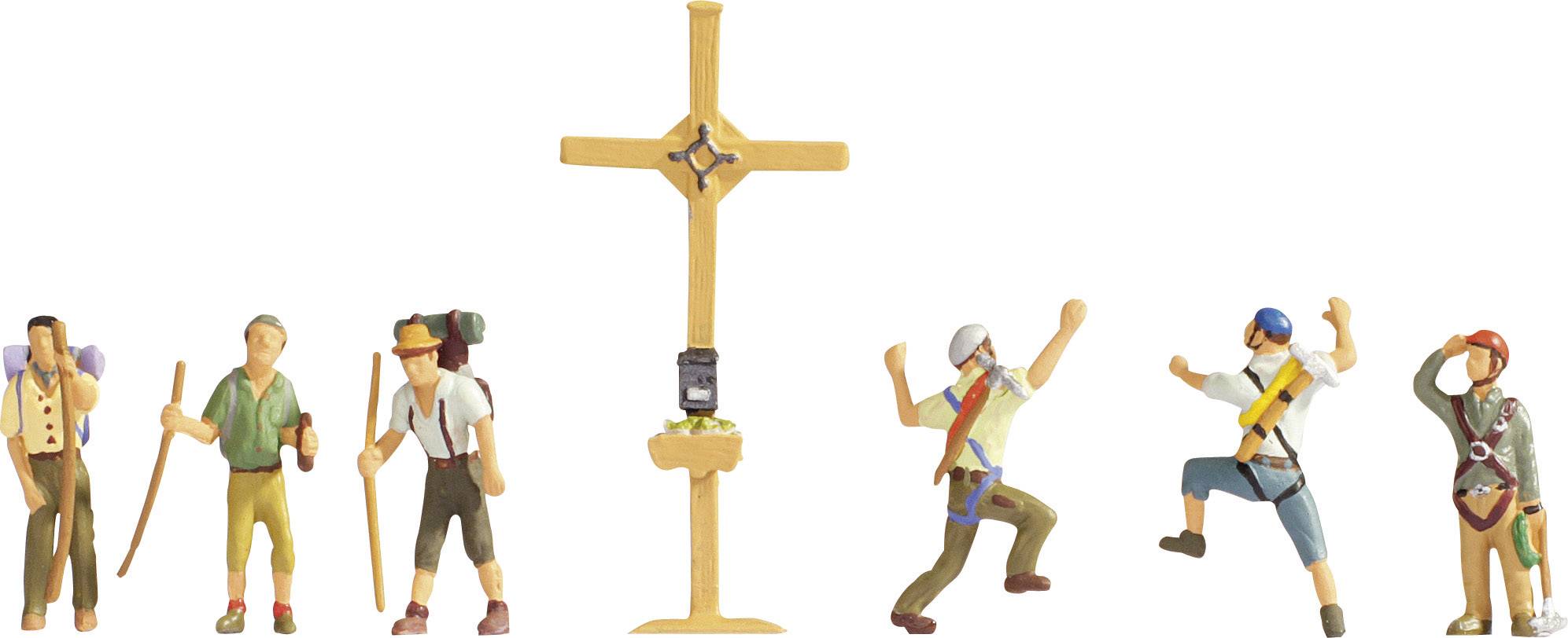 Six miniature figures hiking in traditional costume stand around a wooden wayside cross, two figures cheering enthusiastically.