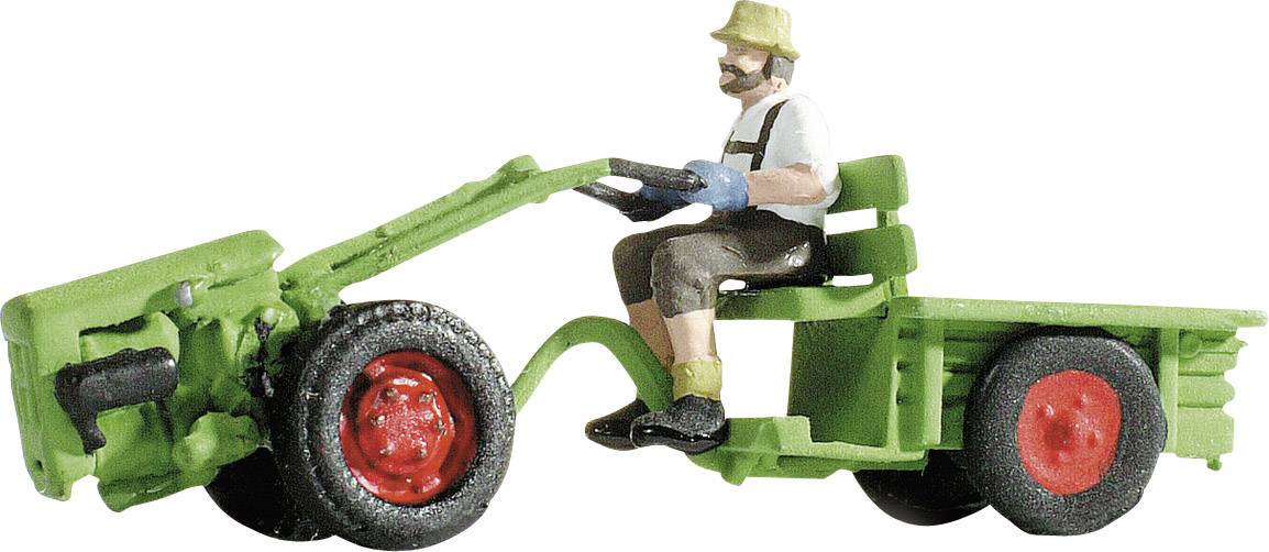 A toy figure of a man on a green tractor with red wheels, dressed in blue and wearing a hat, working outdoors.
