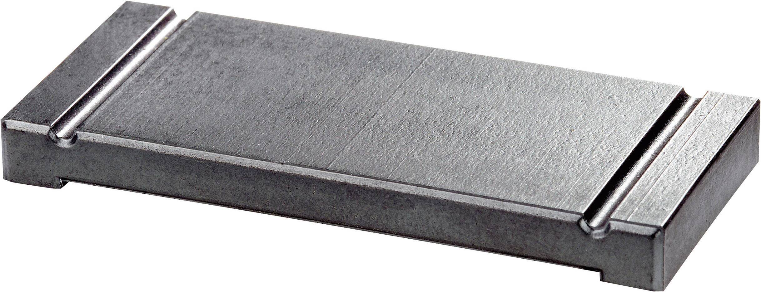 Rechteckiger Metallblock auf einer nicht erkennbaren Oberfläche. Die genaue Funktion oder Verwendungszweck des Blocks ist nicht ersichtlich.