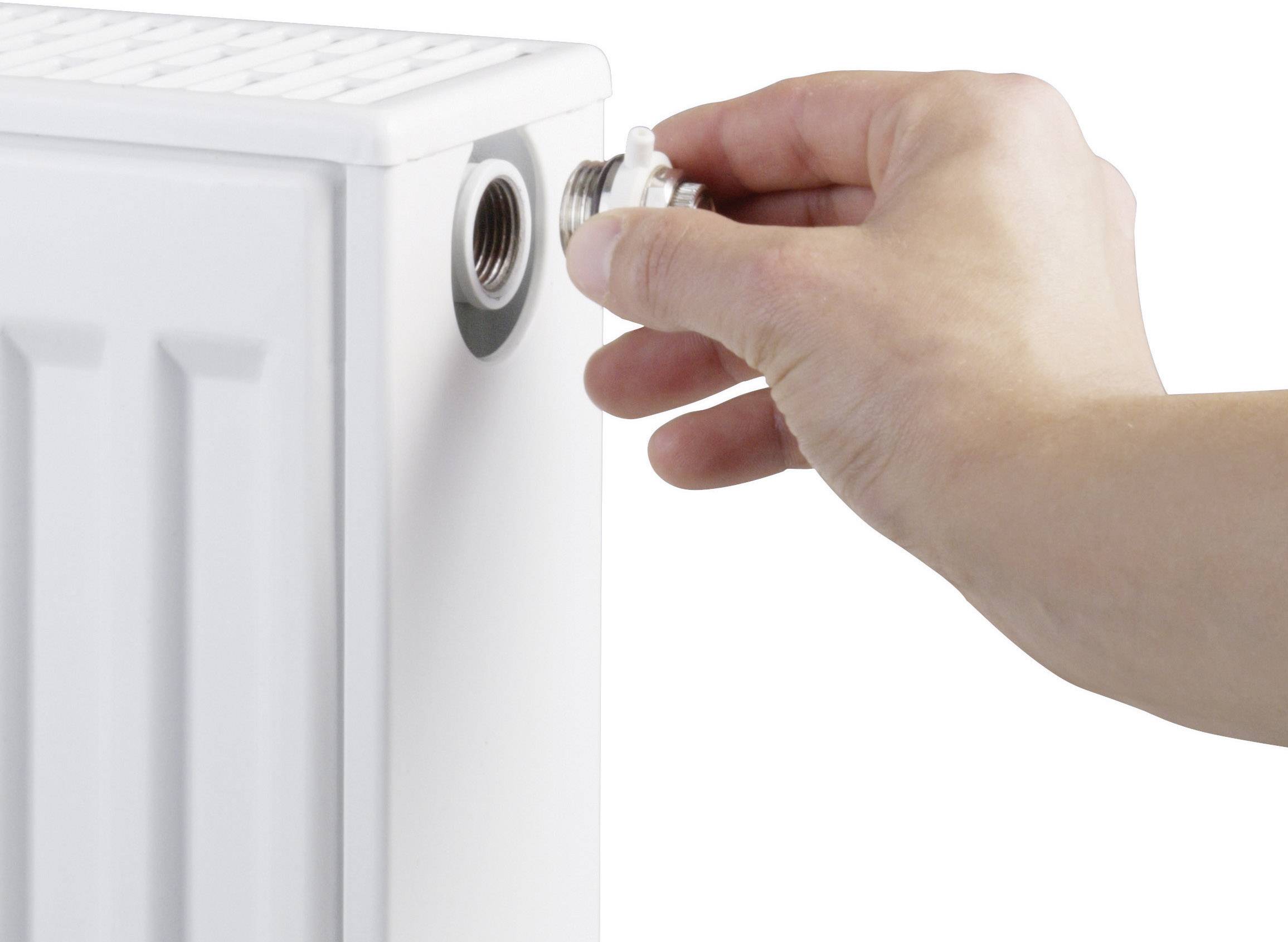 A hand opens a valve on a radiator, likely to release air and optimise heating performance.