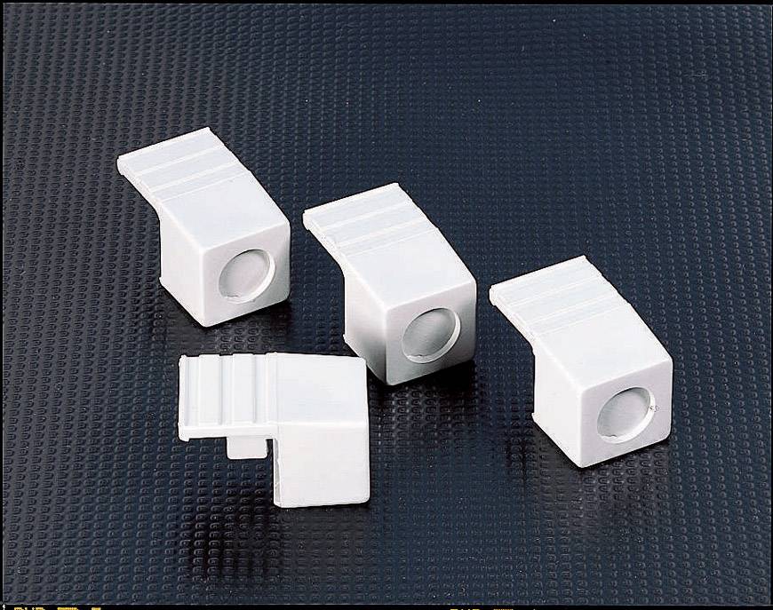 Four rectangular white plastic caps on a black, textured surface, presumably as protective covers for connectors.