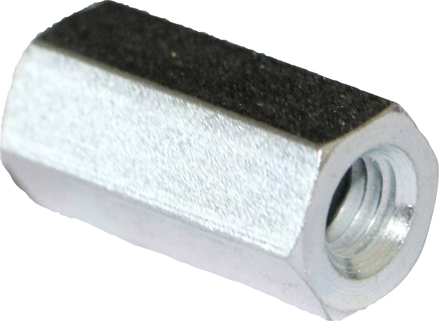 A metal hexagonal nut with internal threading, lying on a white surface sideways, showing the thread opening towards the camera.