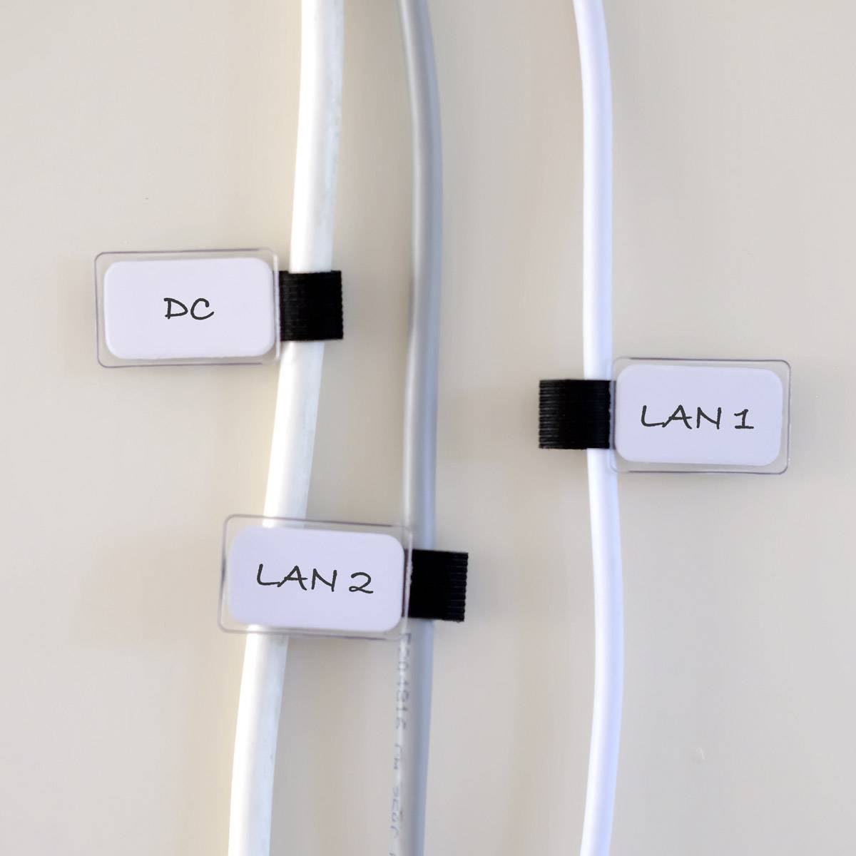 Three cables side by side, each labelled with tags: DC, LAN 2, LAN 1, from left to right.