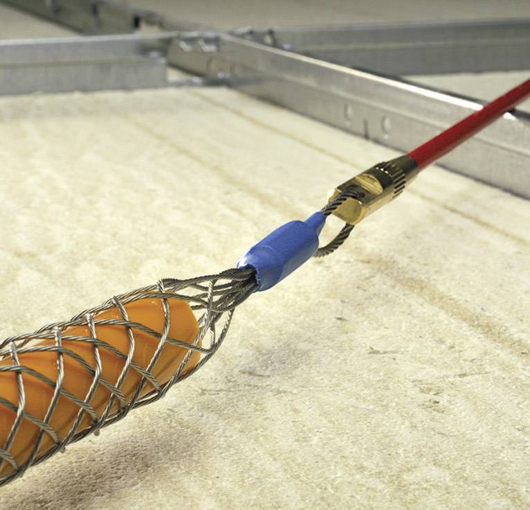 An orange cable is routed through a metal mesh in a ceiling. The metal mesh holds the cable in position.