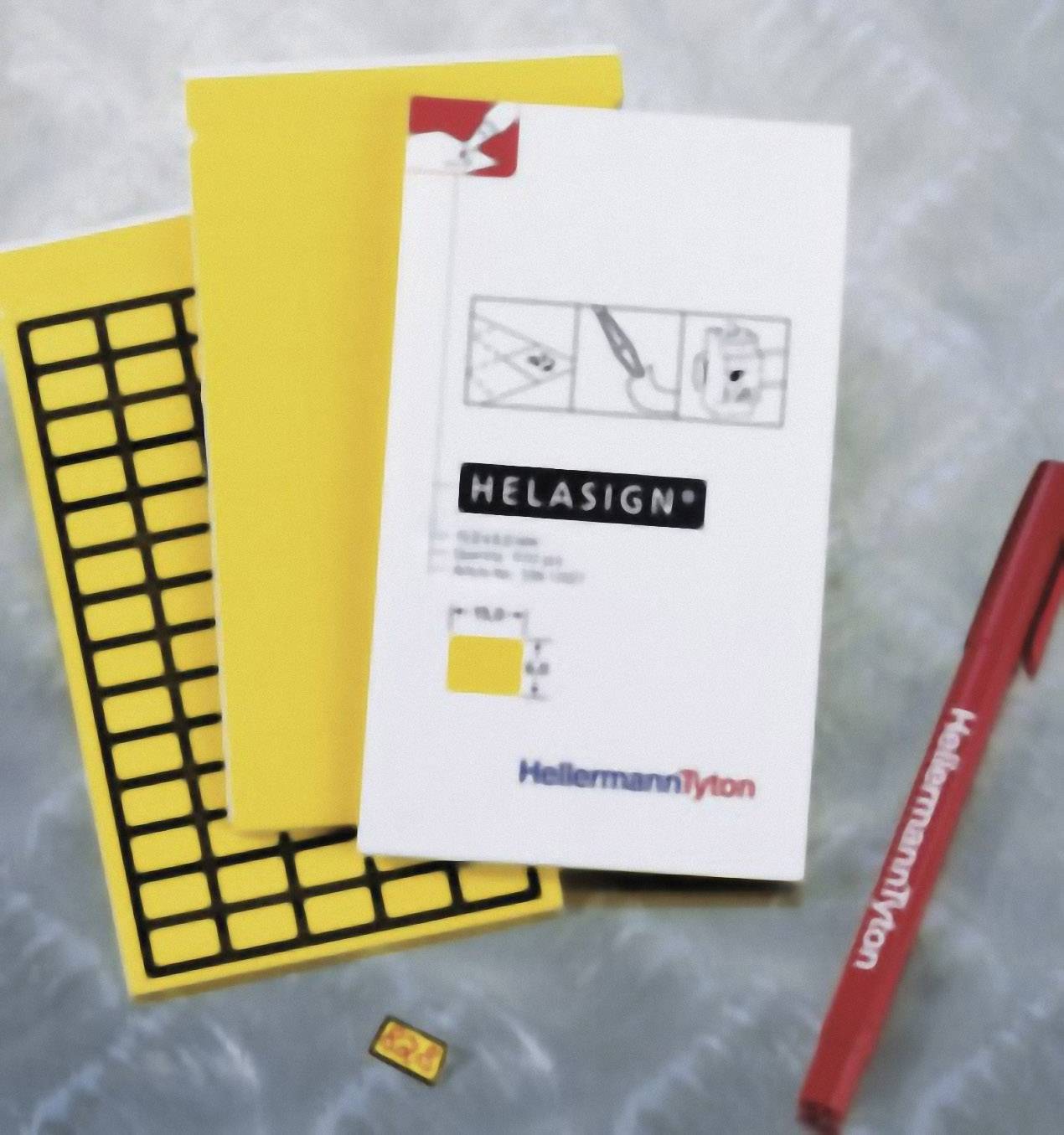 Two yellow notepads, a white notebook with the inscription 'Helasign', a HellermannTyton pen and a small yellow label.