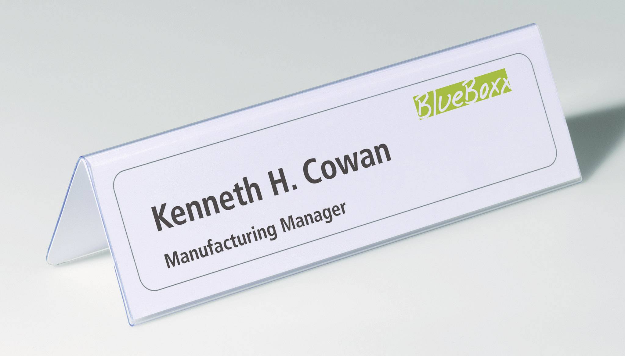 Name badge with the inscription 'Kenneth H. Cowan, Manufacturing Manager' and the company logo 'BlueBoxx'.