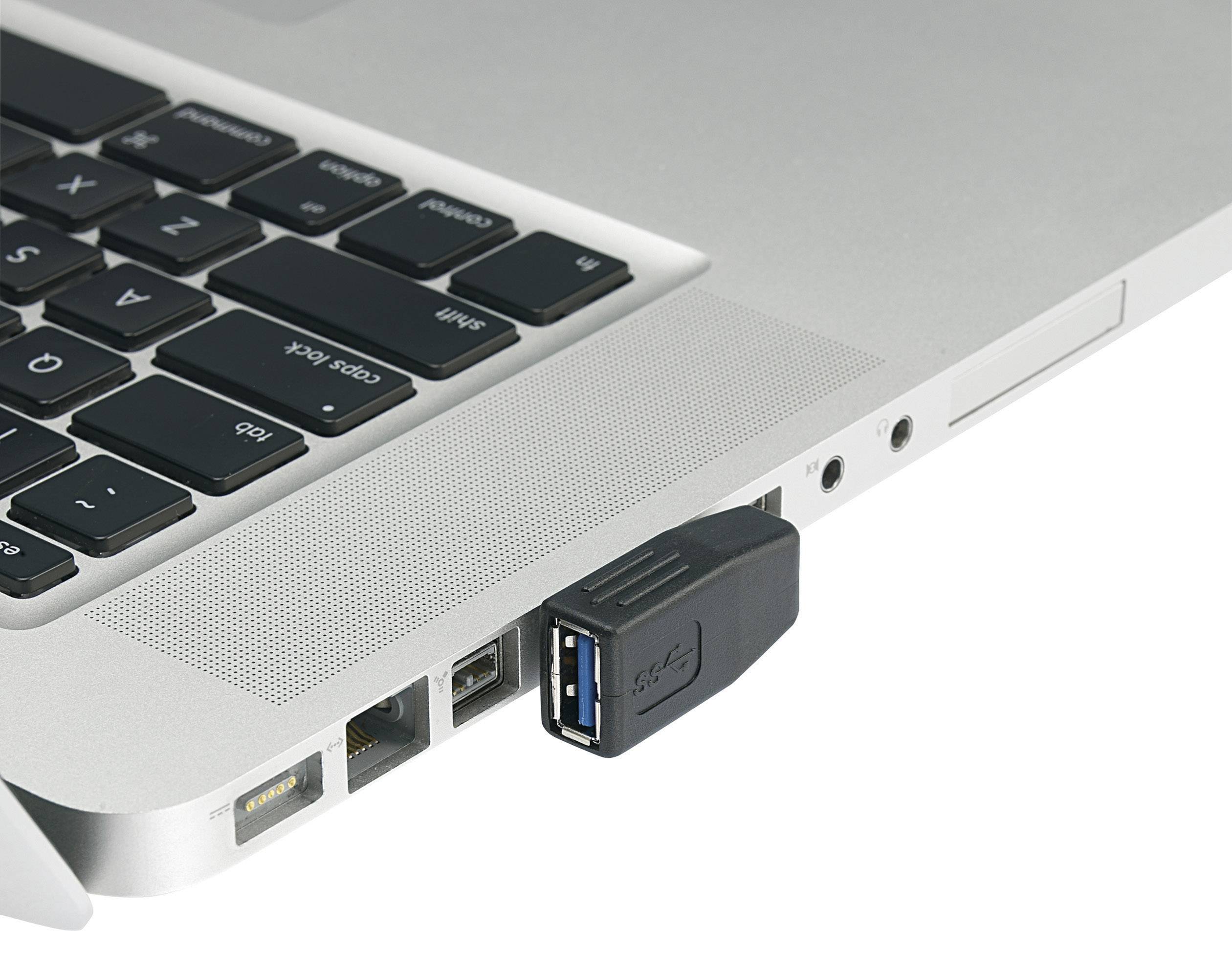 A USB stick is plugged into a laptop. The laptop is silver and shows parts of the keyboard and ports.