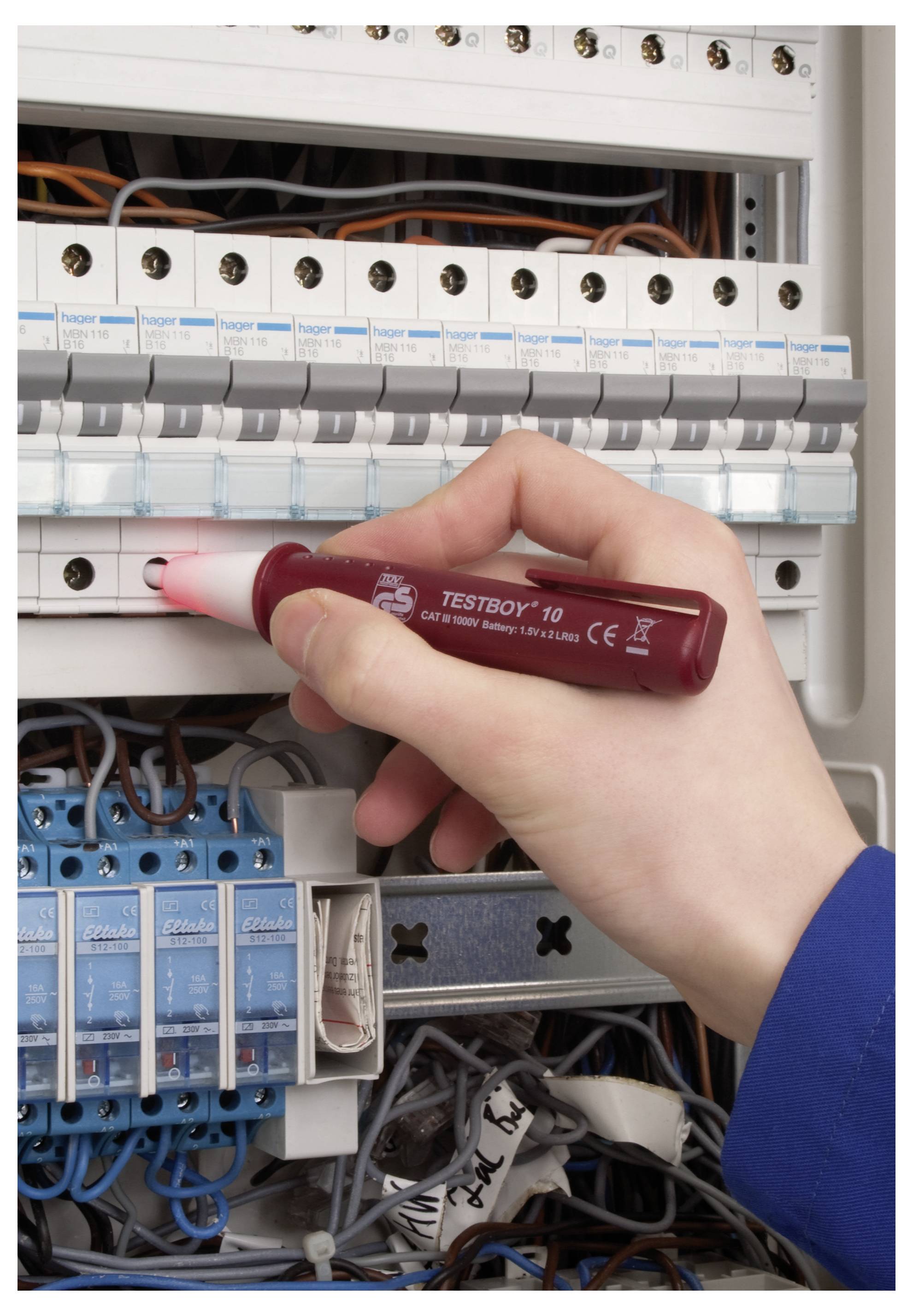 Une personne utilise un testeur de tension dans un panneau électrique, vérifiant les circuits. Le panneau possède plusieurs disjoncteurs et des fils visibles.