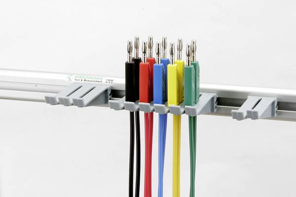 Des pinces crocodile multicolores en bleu, rouge, noir, jaune et vert sont accrochées à intervalles réguliers sur un support métallique.